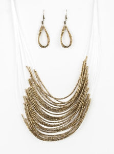 Strand after strand of shimmering brass seed beads fall together to create a bold statement piece. Features an adjustable clasp closure.  Sold as one individual necklace. Includes one pair of matching earrings.