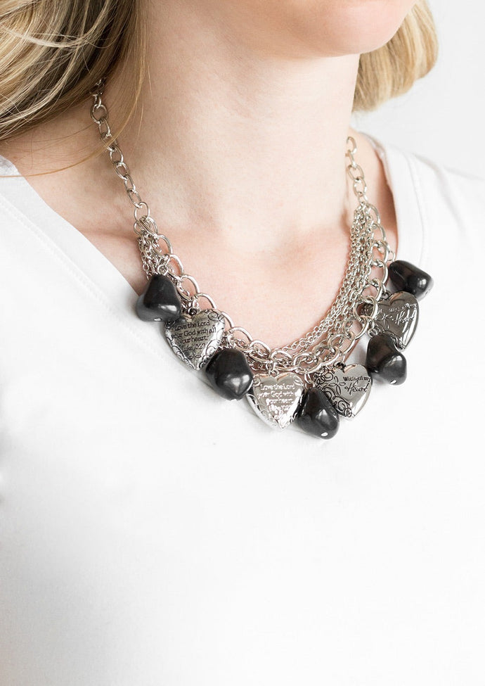 Black faux rocks alternate with heart charms along a chunky silver chain. Hearts are inscribed with the phrase 