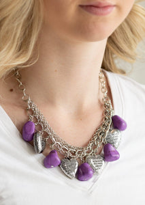 Purple faux rocks alternate with heart charms along a chunky silver chain. Hearts are inscribed with the phrase "With All My Heart" on one side and a short bible verse on the other that reads, "Love the Lord thy God with all your heart. Luke 10:27." Layers of various chains add some edge. Features an adjustable clasp closure.  Sold as one individual necklace. Includes one pair of matching earrings.