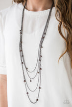 Load image into Gallery viewer, Varying in shape and shimmer, four glistening gunmetal chains drape across the chest. Glassy and pearly metallic beading alternate along the shimmery layers for a refined finish. Features an adjustable clasp closure.  Sold as one individual necklace. Includes one pair of matching earrings.   