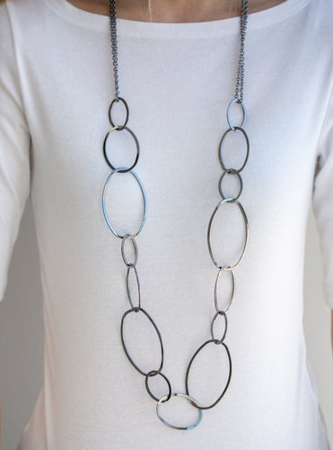 Swinging from doubled gunmetal chains, oversized asymmetrical hoops dramatically link across the chest for a refined industrial look. Features an adjustable clasp closure.  Sold as one individual necklace. Includes one pair of matching earrings.  Always nickel and lead free.