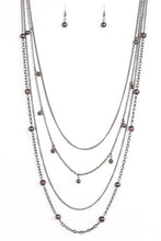 Load image into Gallery viewer, Varying in shape and shimmer, four glistening gunmetal chains drape across the chest. Glassy and pearly metallic beading alternate along the shimmery layers for a refined finish. Features an adjustable clasp closure.  Sold as one individual necklace. Includes one pair of matching earrings.