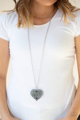 Dotted with glittery black rhinestones, an over sized heart frame radiating with glistening filigree detail swings from the bottom of a lengthened silver chain for a vintage inspired look. Features an adjustable clasp closure.  Sold as one individual necklace. Includes one pair of matching earrings.  Always nickel and lead free.