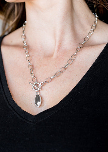 Featuring a regal marquise style cut, a glittery hematite rhinestone swings from the bottom of a silver chain below the collar for a classic look. Features a toggle closure.  Sold as one individual necklace. Includes one pair of matching earrings. 