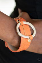 Load image into Gallery viewer, An oval silver ring loops through two belt loop fittings and is studded in place across the front of a spliced orange leather band for a bold urban look. Features an adjustable snap closure.  Sold as one individual bracelet. Always nickel and lead free.