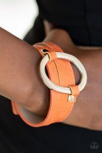 An oval silver ring loops through two belt loop fittings and is studded in place across the front of a spliced orange leather band for a bold urban look. Features an adjustable snap closure.  Sold as one individual bracelet. Always nickel and lead free.
