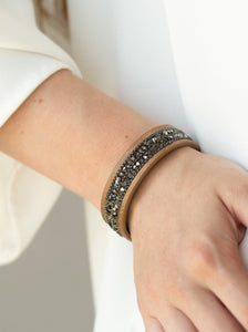 The center of a skinny brown leather band is encrusted in alternating rows of glistening gunmetal ball chain and glittery prism rhinestones for a sassy look. Features an adjustable snap closure.  Sold as one individual bracelet.  Always nickel and lead free. 