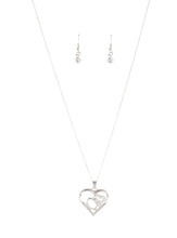 Load image into Gallery viewer, A white rhinestone encrusted heart intertwines with a plain silver heart inside of a larger silver heart frame, creating a romantic pendant at the bottom of a shimmery silver chain. Features an adjustable clasp closure.  Sold as one individual necklace. Includes one pair of matching earrings.
