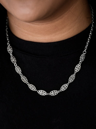 Brushed in an antiqued shimmer, dainty floral charms link below the collar for a seasonal look. Features an adjustable clasp closure.     Includes one pair of matching earrings.