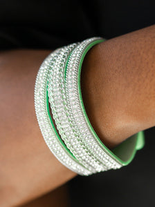 Rows of shimmery silver chains and glassy white rhinestones are encrusted along a green suede band. The glittery band has been spliced into three strands, creating row after row of blinding shimmer for a sassy look. Features an adjustable snap closure.  Sold as one individual bracelet. 