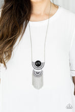 Load image into Gallery viewer, Two interlocking silver half-moon frames give way to a curtain of shimmery silver fringe. The uppermost frame is dotted with an oversized black bead center, adding a dramatic pop of color to the tribal inspired pendant. Features an adjustable clasp closure.  Sold as one individual necklace. Includes one pair of matching earrings.  Always nickel and lead free.