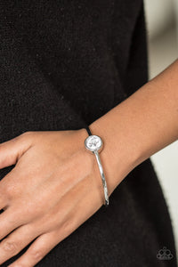A faceted white gem is pressed into the center of a shimmery silver bangle, creating a dramatic centerpiece atop the wrist.  Sold as one individual bracelet.  Always nickel and lead free.