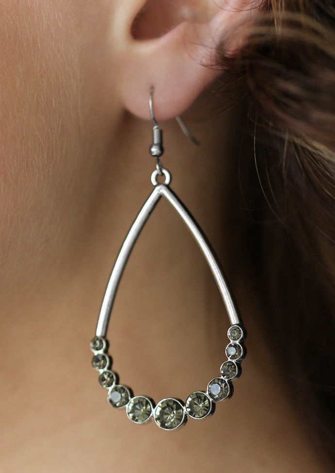 The bottom of a shimmering silver teardrop is encrusted in glassy smoky rhinestones for a dramatic finish. Earring attaches to a standard fishhook fitting.  Sold as one pair of earrings.