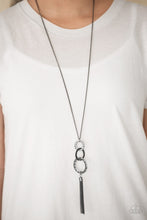 Load image into Gallery viewer, Delicately hammered in glistening textures, shimmery gunmetal hoops swing from the bottom of a shiny gunmetal chain, creating a bold industrial pendant. A shimmery gunmetal tassel swings from the bottom of the stacked pendant for a seasonal finish. Features an adjustable clasp closure.  Sold as one individual necklace. Includes one pair of matching earrings.  Always nickel and lead free.