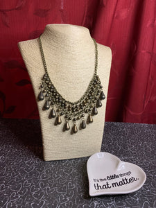 Threaded along metallic rods, stacked brass beads give way to shimmery teardrops. The edgy fringe flawlessly drapes beneath the collar, creating a sassy tapered fringe. Features an adjustable clasp closure.  Sold as one individual necklace. Includes one pair of matching earrings.