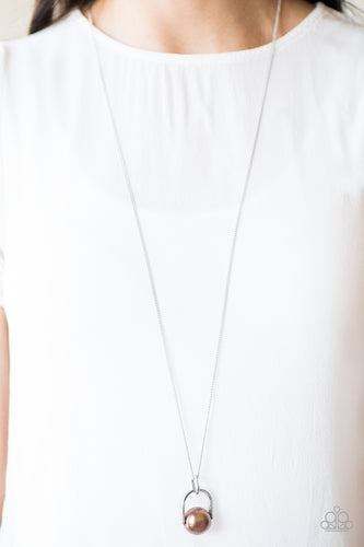 Brushed in a pearlescent shimmer, an oversized brown bead is pinched between a glistening silver frame, creating the illusion of a floating pearl for a dramatic look. Features an adjustable clasp closure.  Sold as one individual necklace. Includes one pair of matching earrings.  Always nickel and lead free.