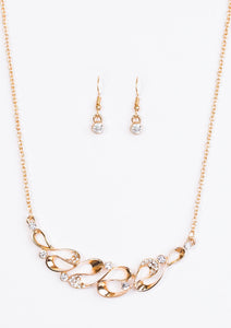 A ribbon of glistening gold loops below the collar, creating a refined pendant. White rhinestones are sprinkled along the rippling ribbons, adding a classic sparkle to the timeless pendant. Features an adjustable clasp closure.  Sold as one individual necklace. Includes one pair of matching earrings.