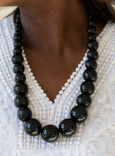 Load image into Gallery viewer, Gradually increasing in size near the center, refreshing black wooden beads are threaded along a black string for a summery look. Features an adjustable sliding knot closure.  Sold as one individual necklace. Includes one pair of matching earrings.