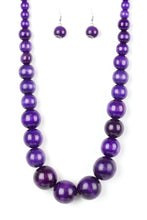 Load image into Gallery viewer, Gradually increasing in size near the center, vivacious purple wooden beads are threaded along a purple string for a summery look. Features an adjustable sliding knot closure.  Sold as one individual necklace. Includes one pair of matching earrings.
