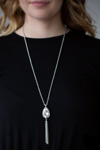 A white teardrop gem swings from the bottom of a lengthened silver chain for a dramatic look. A shimmery silver chain tassel swings from the bottom of the pendant for a glamorous finish. Features an adjustable clasp closure.  Sold as one individual necklace. Includes one pair of matching earrings.  Always nickel and lead free.