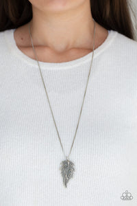 Encrusted in smoky rhinestones and stacked with linear textures, feathery silver leaf pendants swing from the bottom of a lengthened silver chain for a seasonal flair. Features an adjustable clasp closure.  Sold as one individual necklace. Includes one pair of matching earrings.