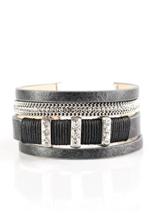 Metallic black leather strands layer across the wrist. Infused with silver chain and white rhinestone accents, black cording knots around a leather strand, securing glittery white rhinestone frames in place for a sassy finish. Features an adjustable clasp closure.  Sold as one individual bracelet.