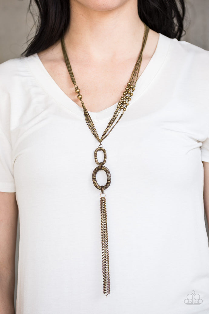 Layers of shimmery brass chains give way to two brass rings featuring rounded box-chain. Infused with an elongated brass tassel, sporadic brass beads are sprinkled along the layers of chain for a flashy asymmetrical finish. Features an adjustable clasp closure.  Sold as one individual necklace. Includes one pair of matching earrings.  Always nickel and lead free.