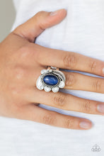 Load image into Gallery viewer, A glowing blue cat&#39;s eye stone is pressed into the center of a shimmery silver frame radiating with a silver feather and glistening white petals, creating a whimsical compilation atop the finger. Features a stretchy band for a flexible fit.  Sold as one individual ring.  Always nickel and lead free.