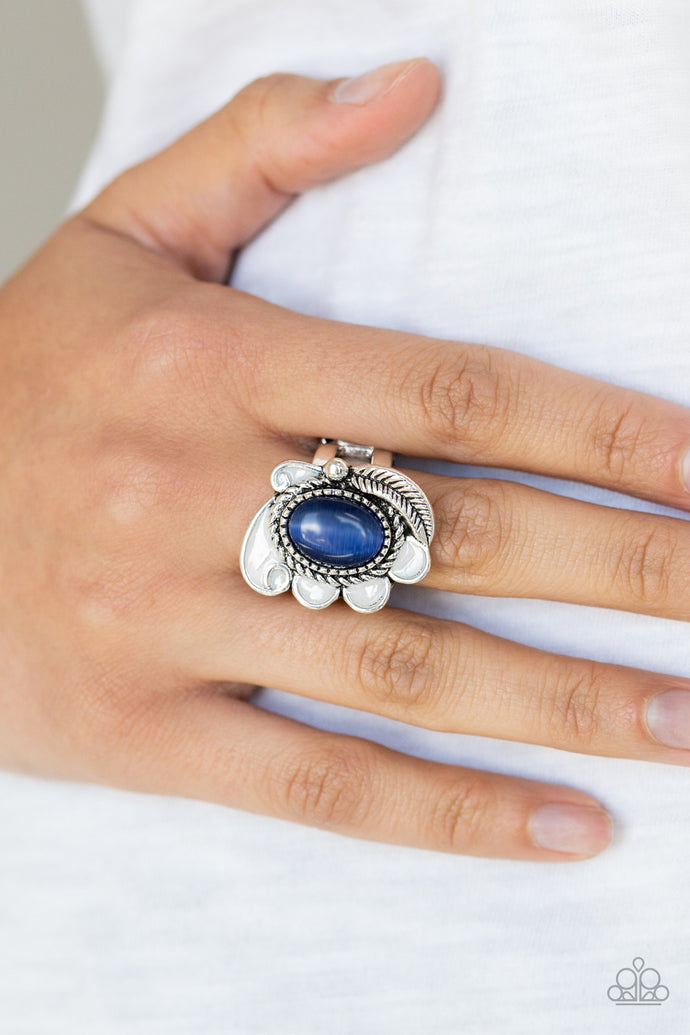 A glowing blue cat's eye stone is pressed into the center of a shimmery silver frame radiating with a silver feather and glistening white petals, creating a whimsical compilation atop the finger. Features a stretchy band for a flexible fit.  Sold as one individual ring.  Always nickel and lead free.