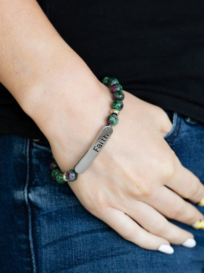 A collection of green stones, dainty silver beads, and a silver plate stamped with the inspirational word, 