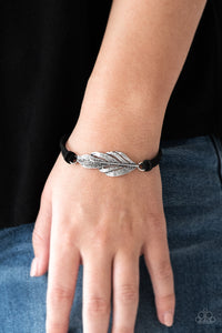 Strands of black suede knot around a shimmery silver feather charm, creating a seasonal pendant atop the wrist. Features an adjustable clasp closure.  Sold as one individual bracelet.  Always nickel and lead free.