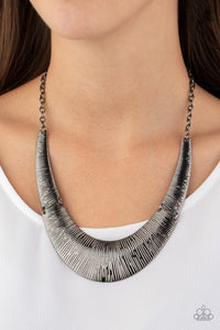 Etched in linear patterns, dramatic gunmetal plates connect below the collar, joining into a fierce crescent-shaped pendant for a statement making look. Features an adjustable clasp closure.  Sold as one individual necklace. Includes one pair of matching earrings.  Always nickel and lead free.