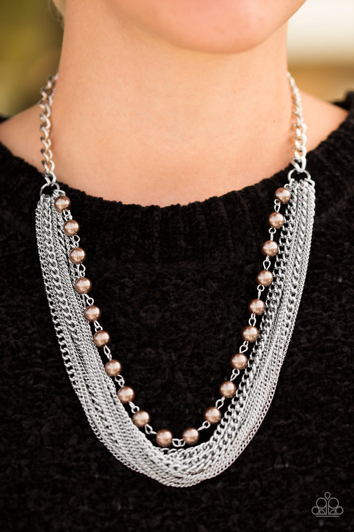 A strand of classic brown pearls gives way to layers of mismatched silver chain, creating a fierce look below the collar. Features an adjustable clasp closure.  Sold as one individual necklace. Includes one pair of matching earrings.