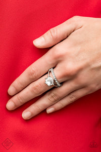 An oversized white rhinestone dots the center of a dainty silver band, as a second band lined with glittery white rhinestones runs parallel, resulting in a glamorously stacked look. Features a dainty stretchy band for a flexible fit.  Sold as one individual ring.  Fiercely 5th Avenue March 2020 Always nickel and lead free. 