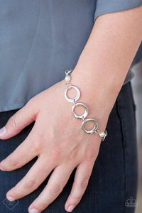 Asymmetrical silver hoops connect with pearly white beads across the wrist for a refined look.