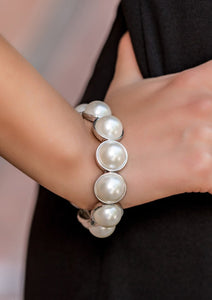  Pearly white beads are pressed into sleek silver frames and threaded along a stretchy band around the wrist to create a playfully refined look.