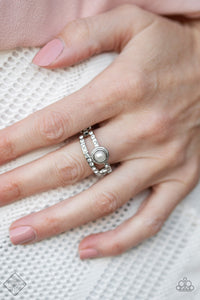 Two skinny silver bars decorated in tiny white rhinestones run parallel to each other, creating a layered band. A tiny white pearl encircled by a classic silver frame sits atop one of the silver bars, creating a refined centerpiece. Features a dainty stretchy band for a flexible fit.