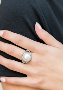 A pearly white bead is pressed into the center of a classic silver frame, creating a classic statement piece that sits atop the finger. Features a dainty stretchy band for a flexible fit.