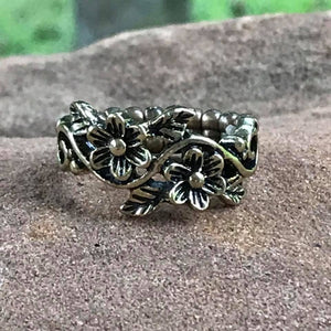 Shimmery brass flowers create a whimsical band across the finger. Features a dainty stretchy band for a flexible fit.  Sold as one individual ring.  Always nickel and lead free.