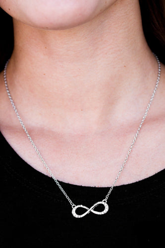 Encrusted in sections of glittery white rhinestones, a dainty silver ribbon swirls into a glistening infinity charm below the collar in a timeless fashion. Features an adjustable clasp closure.  Sold as one individual necklace. Includes one pair of matching earrings.  