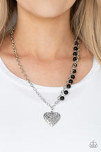 Load image into Gallery viewer, Swirling with filigree details, a whimsical heart pendant swings from the bottom of a shimmery silver chain below the collar. A single strand of shiny black beads drape down one side for a refined asymmetrical finish. Features an adjustable clasp closure.  Sold as one individual necklace. Includes one pair of matching earrings.  Always nickel and lead free.