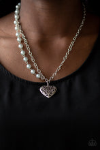 Load image into Gallery viewer, Swirling with filigree details, a whimsical heart pendant swings from the bottom of a shimmery silver chain below the collar. A single strand of pearly silver beads drape down one side for a refined asymmetrical finish. Features an adjustable clasp closure.  Sold as one individual necklace. Includes one pair of matching earrings.  Always nickel and lead free