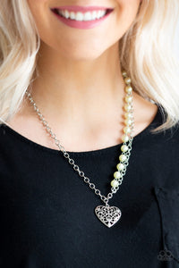 Swirling with filigree details, a whimsical heart pendant swings from the bottom of a shimmery silver chain below the collar. A single strand of pearly yellow beads drape down one side for a refined asymmetrical finish. Features an adjustable clasp closure.  Sold as one individual necklace. Includes one pair of matching earrings.  Always nickel and lead free