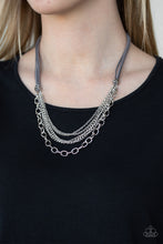 Load image into Gallery viewer, Suspended between strips of earthy gray suede, mismatched strands of silver layer below the collar for a spunky industrial look. Features an adjustable clasp closure.  Sold as one individual necklace. Includes one pair of matching earrings.  Always nickel and lead free