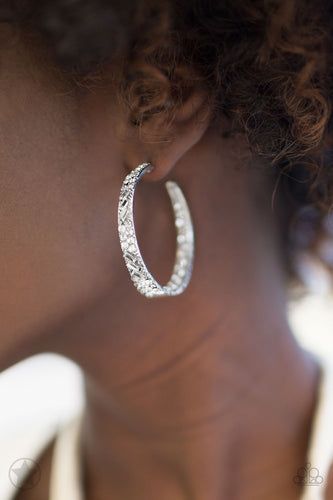 The front facing surface of a chunky silver hoop is dipped in brilliantly sparkling rhinestones while light-catching texture wraps around the back. The interior of the hoop features the opposite pattern, creating the illusion of a full hoop of blinding rhinestones. Earring attaches to a standard post fitting. Hoop measures 1 3/4