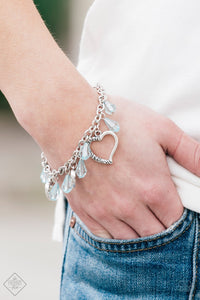 Crystal-like teardrops in the spring hue of Blue Radiance drip from the bottom of a shimmery silver chain. Stamped in ornate patterns, glistening silver heart silhouettes trickle between the colorful accents, creating a whimsical fringe around the wrist. Features an adjustable clasp closure.