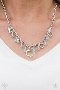 Crystal-like teardrops in the refreshing shade of Blue Radiance drip from the bottom of a shimmery silver chain. Stamped in ornate patterns, glistening silver heart silhouettes trickle between the colorful accents, creating a whimsical fringe below the collar. Features an adjustable clas