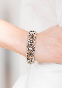 Brushed in an antiqued shimmer, ornate silver frames are threaded along elastic stretchy bands and linked around the wrist for a tribal inspired look.  Sold as one individual bracelet.