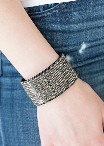 Row after row of glittery hematite rhinestones are encrusted along a thick black suede band, creating blinding shimmer across the wrist. Features an adjustable snap closure.  Sold as one individual bracelet.  