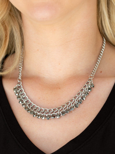 A fringe of glittery hematite rhinestones swings from the bottom of a bold silver chain below the collar for a fierce look. Features an adjustable clasp closure.  Sold as one individual necklace. Includes one pair of matching earrings.  